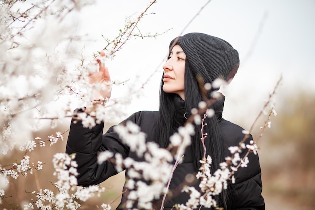 Mulher jovem e bonita no jardim de flores de cerejeira florescendo