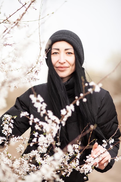 Mulher jovem e bonita no jardim de flores de cerejeira florescendo