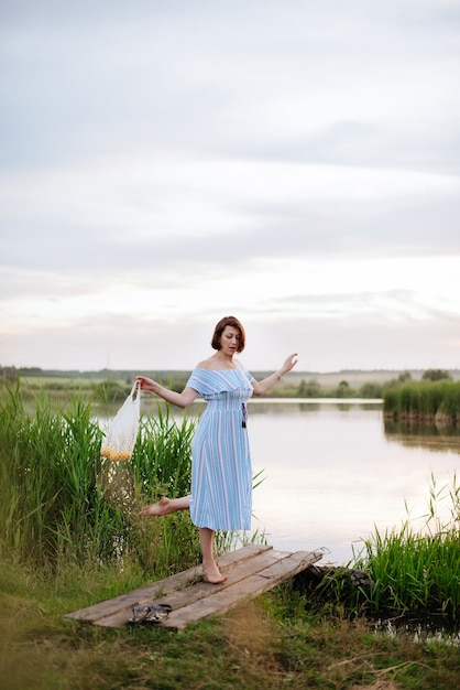 Mulher jovem e bonita no lago ao pôr do sol