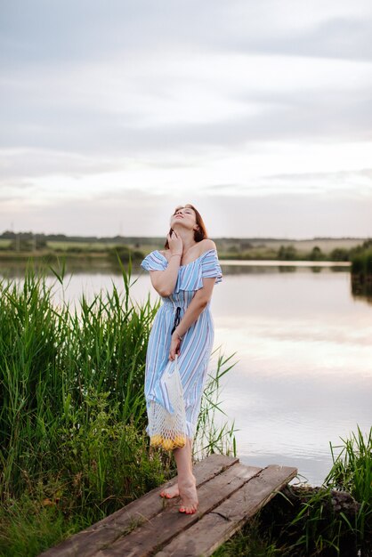 Mulher jovem e bonita no lago ao pôr do sol