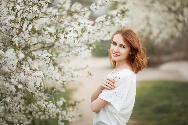 Mulher jovem e bonita no pomar de cerejeiras florescendo na primavera