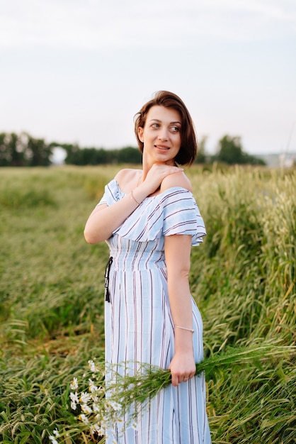 Mulher jovem e bonita no verão em um campo de trigo