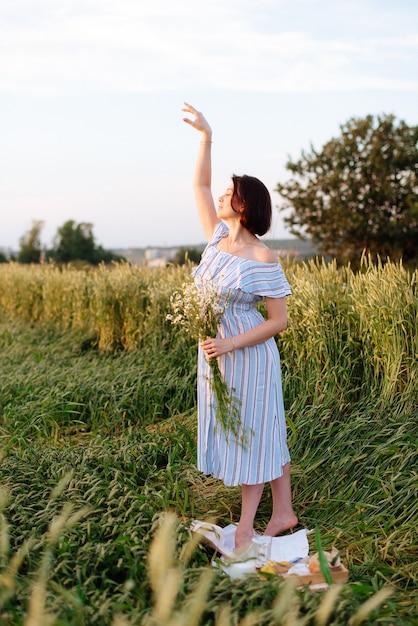 Mulher jovem e bonita no verão em um campo de trigo