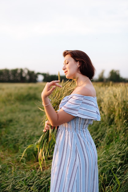 Mulher jovem e bonita no verão em um campo de trigo