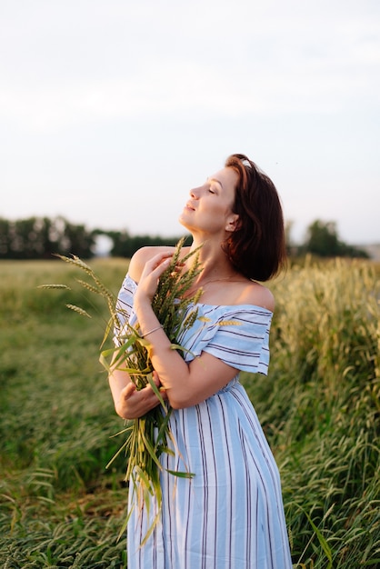 Mulher jovem e bonita no verão em um campo de trigo