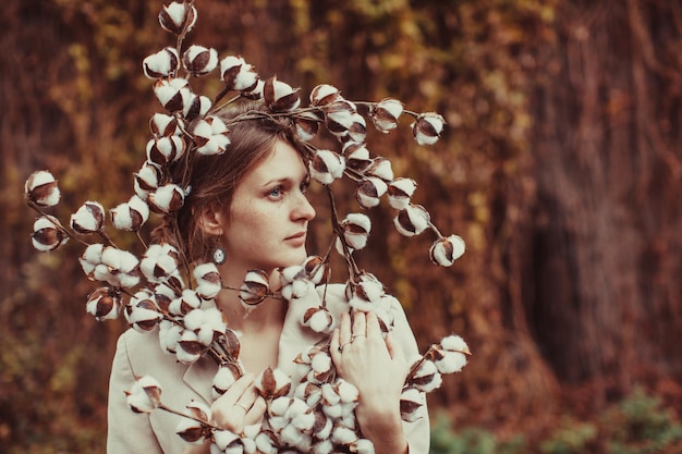 Mulher jovem e bonita no vestido boho e coroa de flores de algodão.