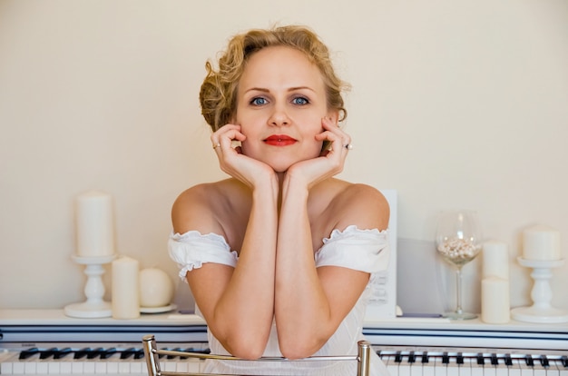 Foto mulher jovem e bonita no vestido branco perto de piano