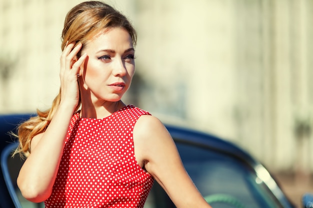 Mulher jovem e bonita no vestido vintage com auto retrô