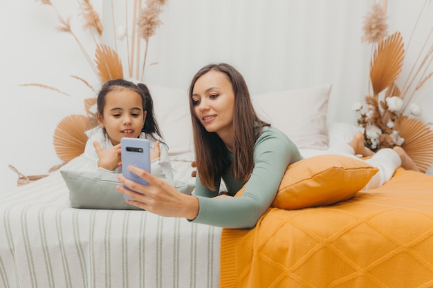 Mulher jovem e bonita olhando para o telefone enquanto estava deitada na cama em casa