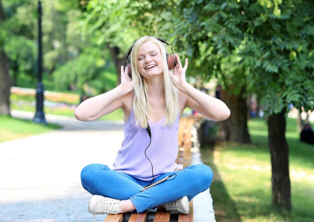 Mulher jovem e bonita ouvindo música no parque