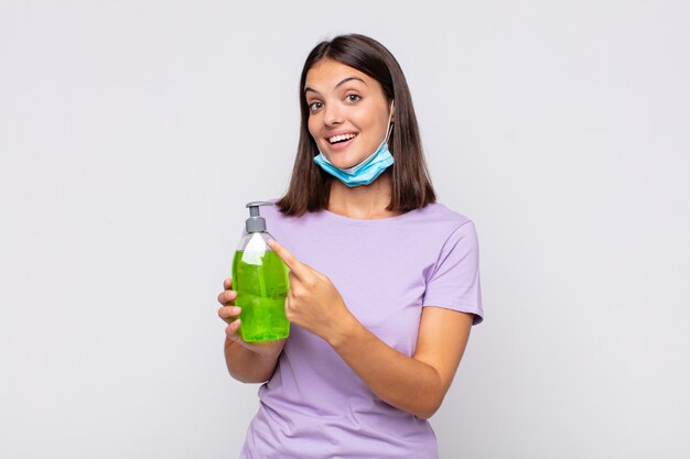 Mulher jovem e bonita parecendo animada e surpresa, apontando para o lado e para cima para copiar o espaço