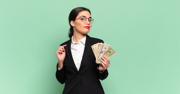 Mulher jovem e bonita parecendo arrogante, bem-sucedida, positiva e orgulhosa, apontando para si mesma. conceito de negócios e notas