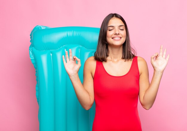 Foto mulher jovem e bonita parecendo concentrada e meditando, sentindo-se satisfeita e relaxada, pensando ou fazendo uma escolha