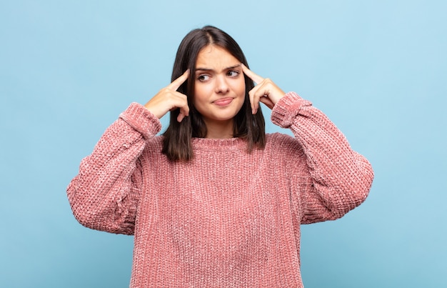 Mulher jovem e bonita parecendo concentrada e pensando seriamente em uma ideia, imaginando uma solução para um desafio ou problema