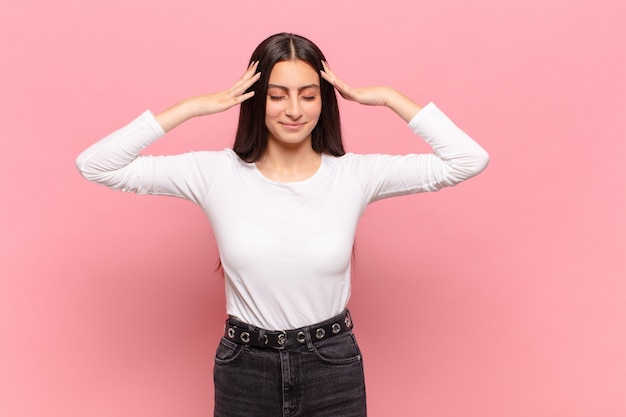 Mulher jovem e bonita parecendo concentrada, pensativa e inspirada, pensando e imaginando com as mãos na testa