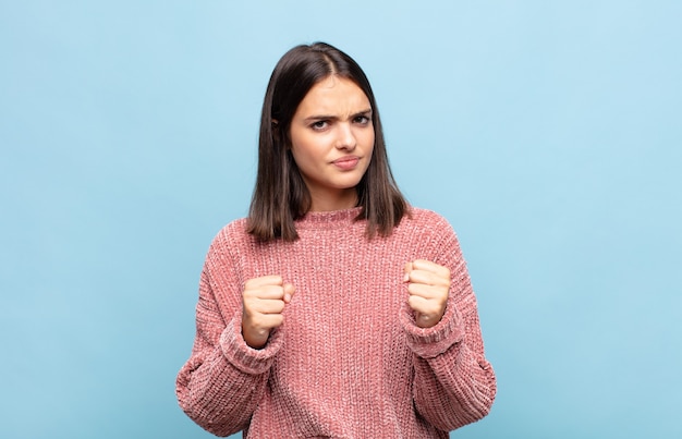 Mulher jovem e bonita parecendo confiante, irritada, forte e agressiva isolada