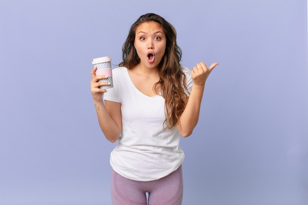 Mulher jovem e bonita parecendo espantada com a descrença e segurando um café