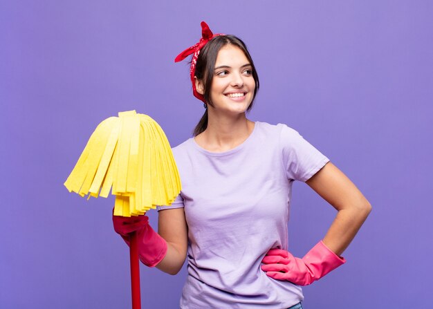 Mulher jovem e bonita parecendo feliz, alegre e confiante, sorrindo com orgulho e olhando para o lado com as duas mãos na cintura