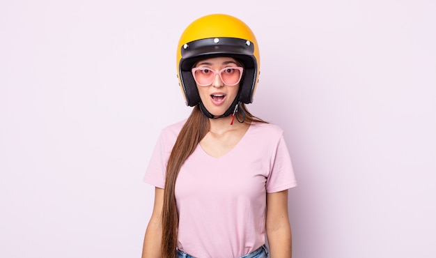 Mulher jovem e bonita parecendo muito chocada ou surpresa. piloto de moto e capacete