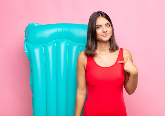 Mulher jovem e bonita parecendo orgulhosa, confiante e feliz, sorrindo e apontando para si mesma ou fazendo o sinal número um