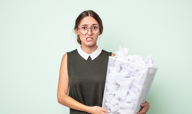 Foto mulher jovem e bonita parecendo perplexa e confusa. conceito de lixo de bolas de papel