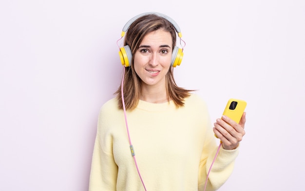 Mulher jovem e bonita parecendo perplexa e confusa. fones de ouvido e conceito de telefone