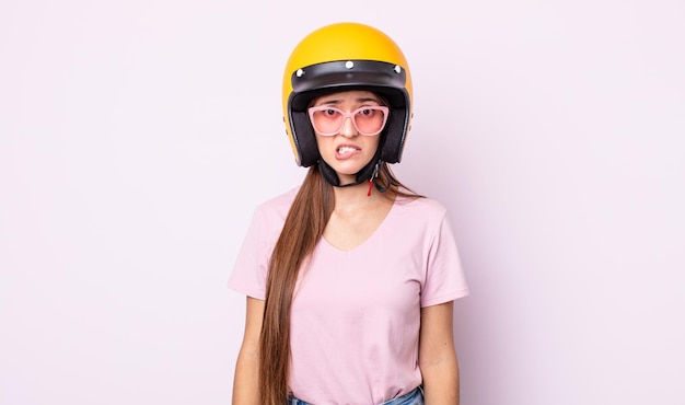 Mulher jovem e bonita parecendo perplexa e confusa. piloto de moto e capacete