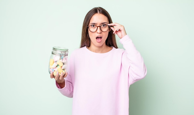 Mulher jovem e bonita parecendo surpresa, percebendo um novo pensamento, ideia ou conceito. conceito de balas de geleia