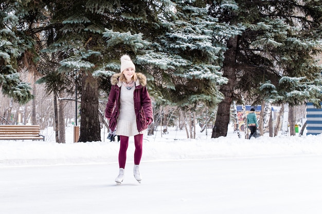 Mulher jovem e bonita patinando no parque de inverno nevado