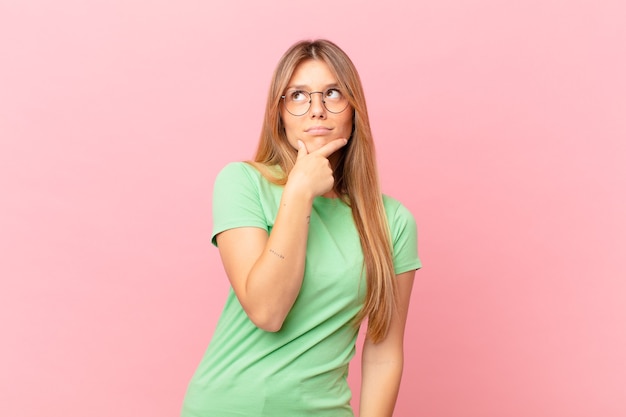 Mulher jovem e bonita pensando, sentindo-se duvidosa e confusa