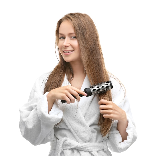 Foto mulher jovem e bonita penteando o cabelo depois do banho na parede branca