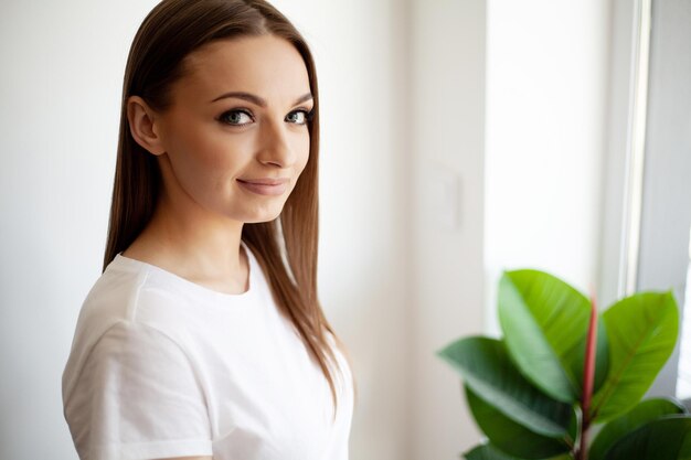 Mulher jovem e bonita perto da janela em casa