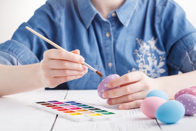 Mulher jovem e bonita pintando ovos de Páscoa. Ambiente acolhedor em casa. Páscoa