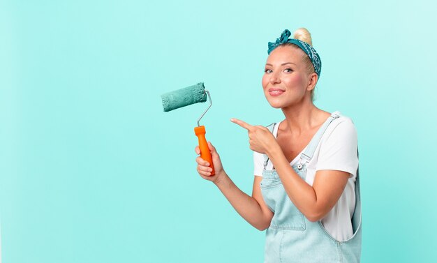 Mulher jovem e bonita pintando uma parede com um rolo