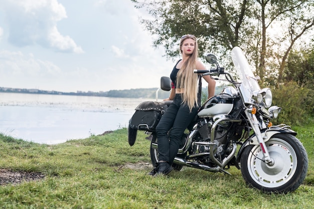 Mulher jovem e bonita posando com moto do lado de fora