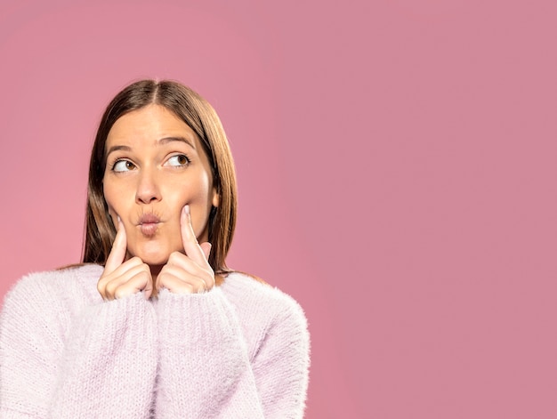 Foto mulher jovem e bonita posando com papel de parede rosa nas costas