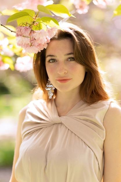 Mulher jovem e bonita posando em um jardim de sakura florescendo.