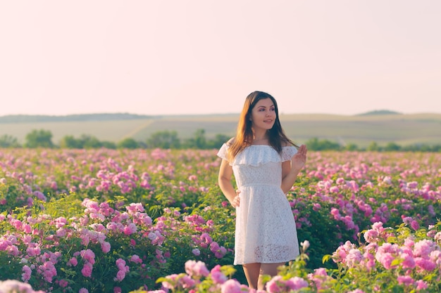 Mulher jovem e bonita posando perto de rosas em um jardim.