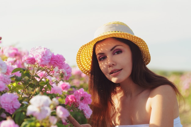 Mulher jovem e bonita posando perto de rosas em um jardim.