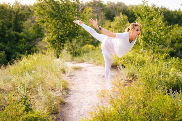 Mulher jovem e bonita praticando ioga em pé em Warrior três exercícios Virabhadrasana III pose