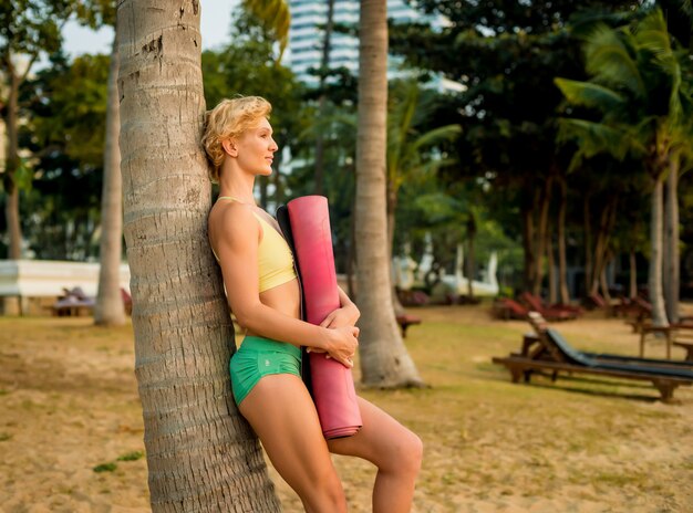Mulher jovem e bonita praticar ioga na praia. Exercício de manhã cedo