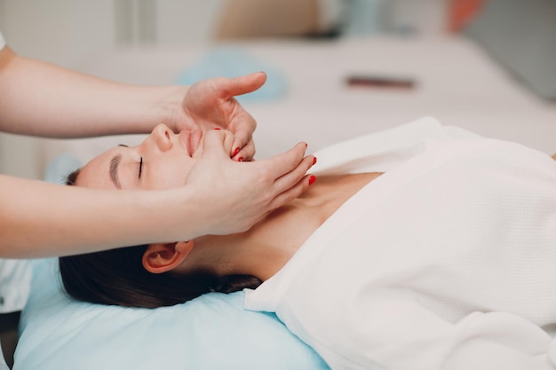 Mulher jovem e bonita recebendo massagem de tratamento facial em salão de spa de beleza