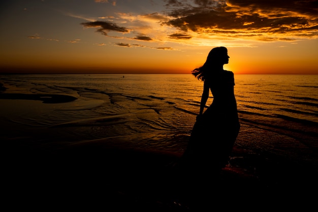 Foto mulher jovem e bonita relaxando ao pôr do sol