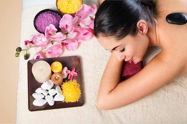 Mulher jovem e bonita relaxando com massagem com pedras no spa de beleza