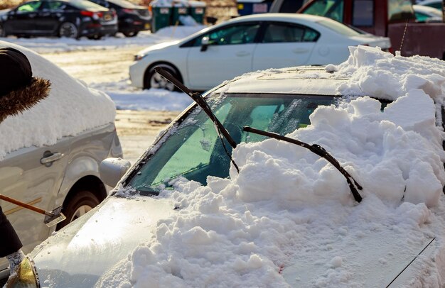 Mulher jovem e bonita removendo a neve de seu carro