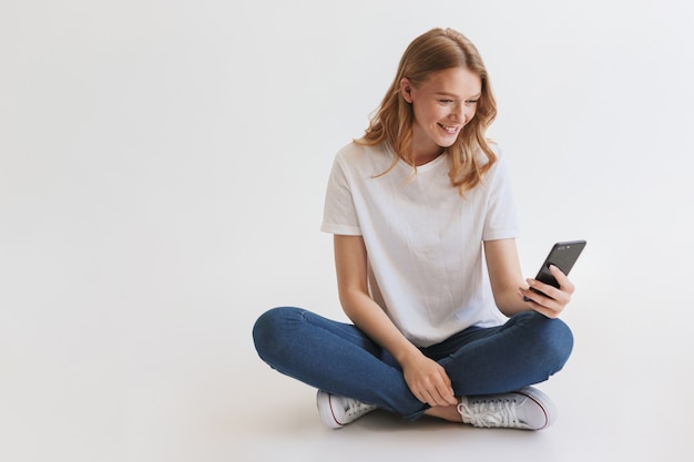 Mulher jovem e bonita ruiva fofa usando telefone celular.