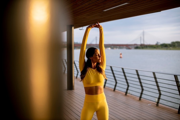 Mulher jovem e bonita se espreguiçando à beira do rio