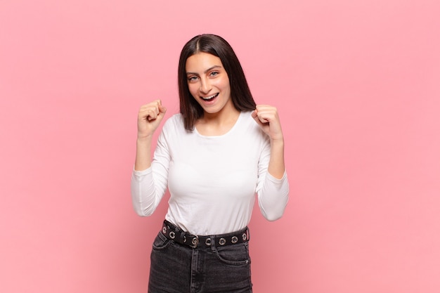 Mulher jovem e bonita se sentindo chocada, animada e feliz, rindo e comemorando o sucesso, dizendo uau!