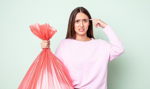 Mulher jovem e bonita se sentindo confusa e intrigada, mostrando que você é louco. conceito de lixo