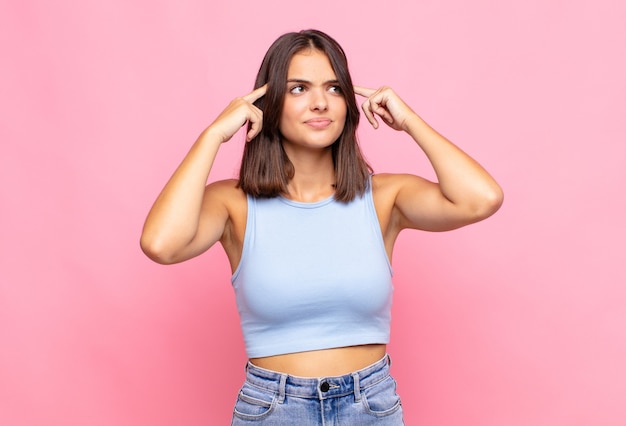 Mulher jovem e bonita se sentindo confusa ou em dúvida, concentrada em uma ideia, pensando muito, procurando copiar o espaço ao lado